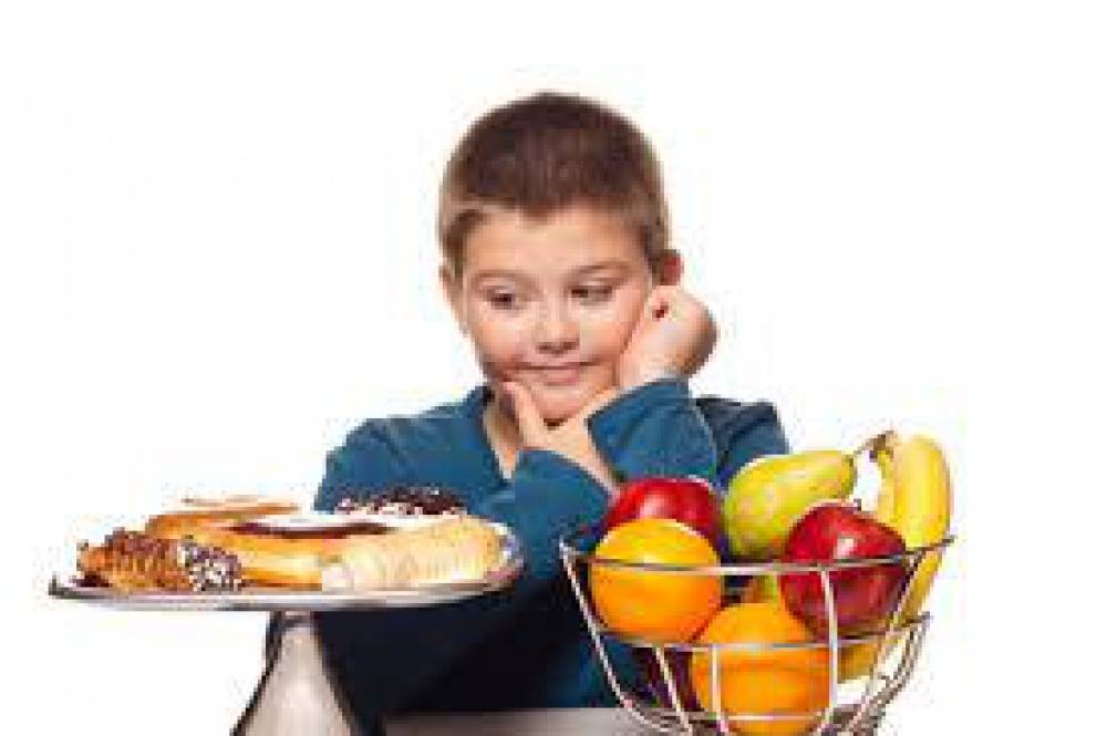Zdjęcie: Chłopiec patrzący na paterę z ciastkami, a obok stos owoców